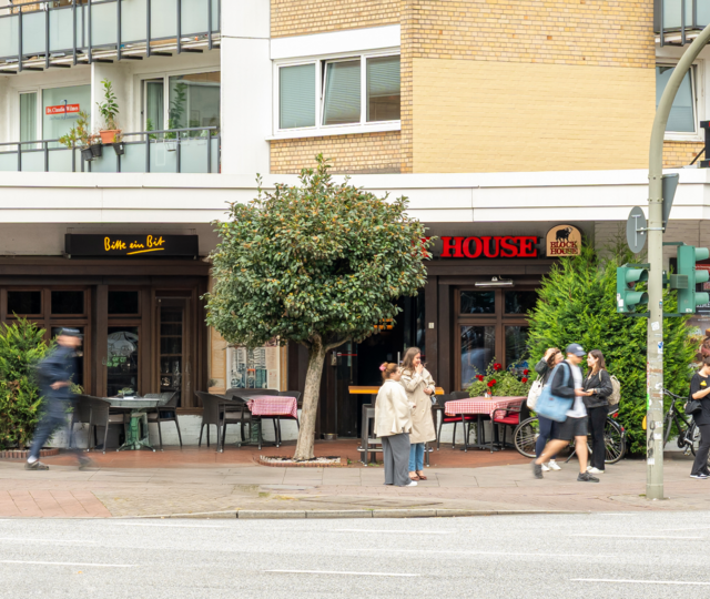 BLOCK HOUSE Hamburg Eppendorf Außenansicht des BLOCK HOUSE Hamburg-Eppendorf mit Terrasse und Passanten an der Straße.