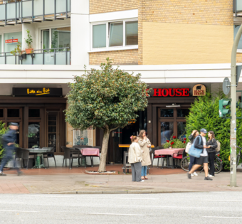 BLOCK HOUSE Hamburg Eppendorf Außenansicht des BLOCK HOUSE Hamburg-Eppendorf mit Terrasse und Passanten an der Straße.
