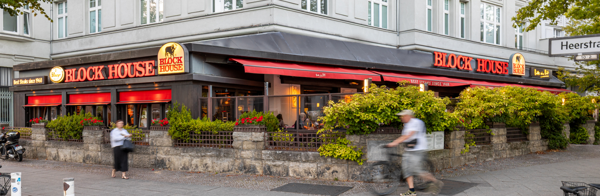 BLOCK HOUSE Berlin Theodor-Heuss-Platz – Steakhouse mit Terrasse Terrasse des BLOCK HOUSE Berlin Theodor-Heuss-Platz mit Tischen und Gästen vor dem Steakhouse