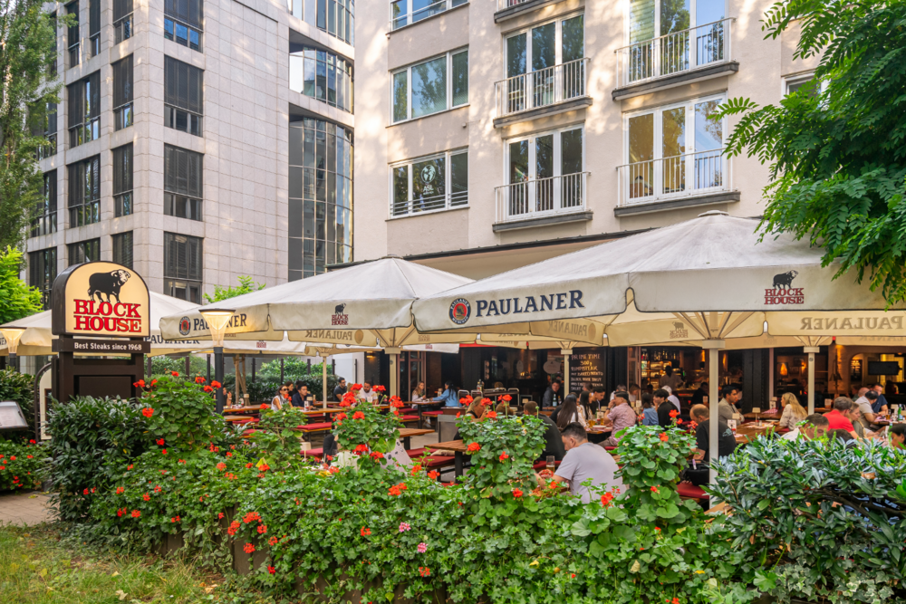 BLOCK HOUSE München Leopoldstraße – sonnengeschützte Terrasse Sonnengeschützte Terrasse des BLOCK HOUSE München Leopoldstraße mit Gästen und Sonnenschirmen vor dem Steakhouse